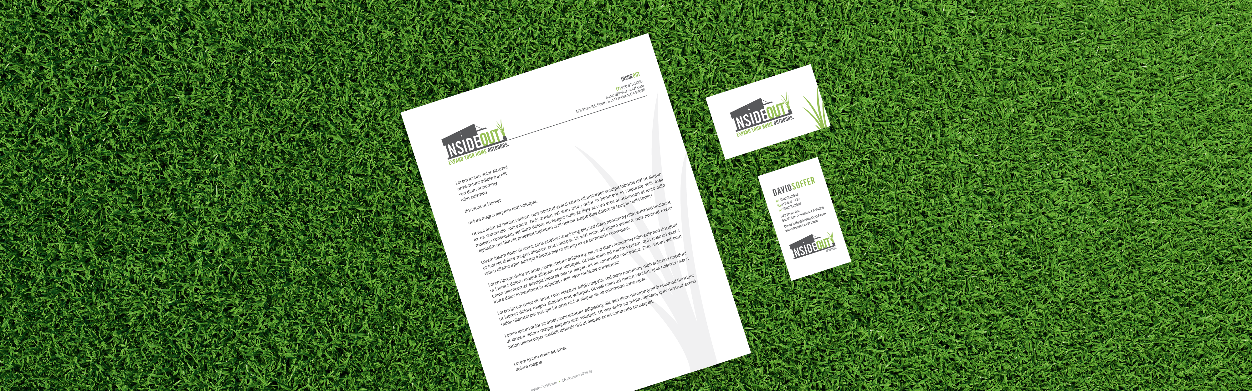 A set of printed corporate identity materials, including a letterhead, business cards, and a booklet or brochure, is displayed inside out on a green grass background.