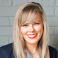 Smiling woman with blonde hair, wearing a business suit, and red lipstick, known as the Keto Girl Nutritionist.