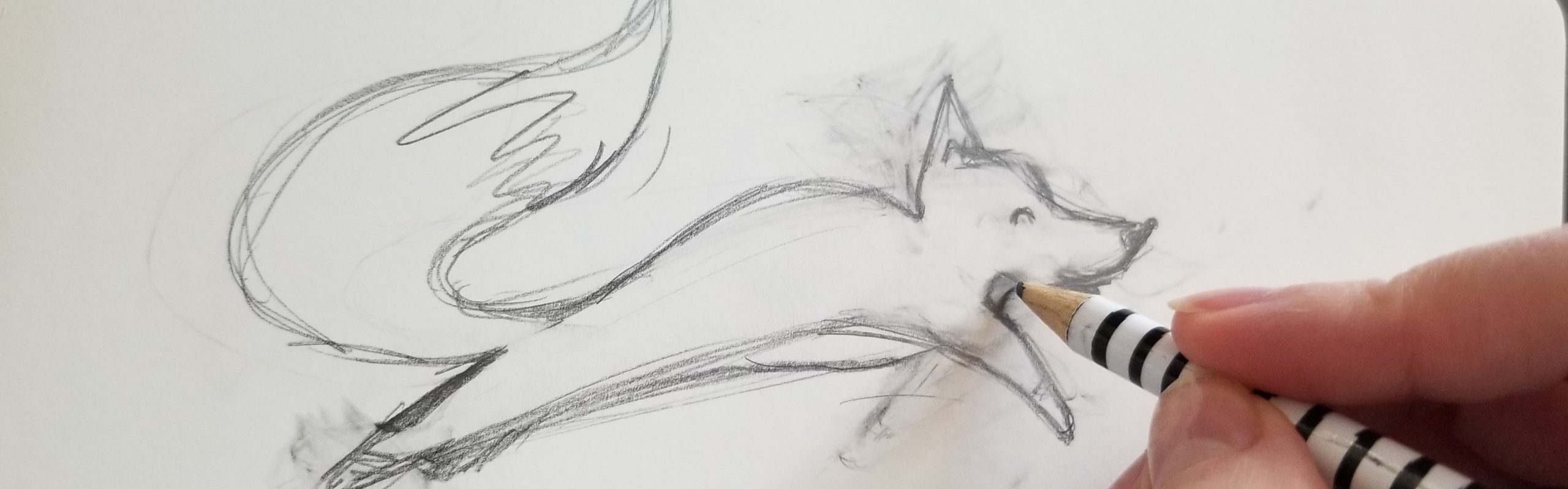 A hand holding a pencil sketches the figure of a little fox on a piece of paper for Fox Therapy.