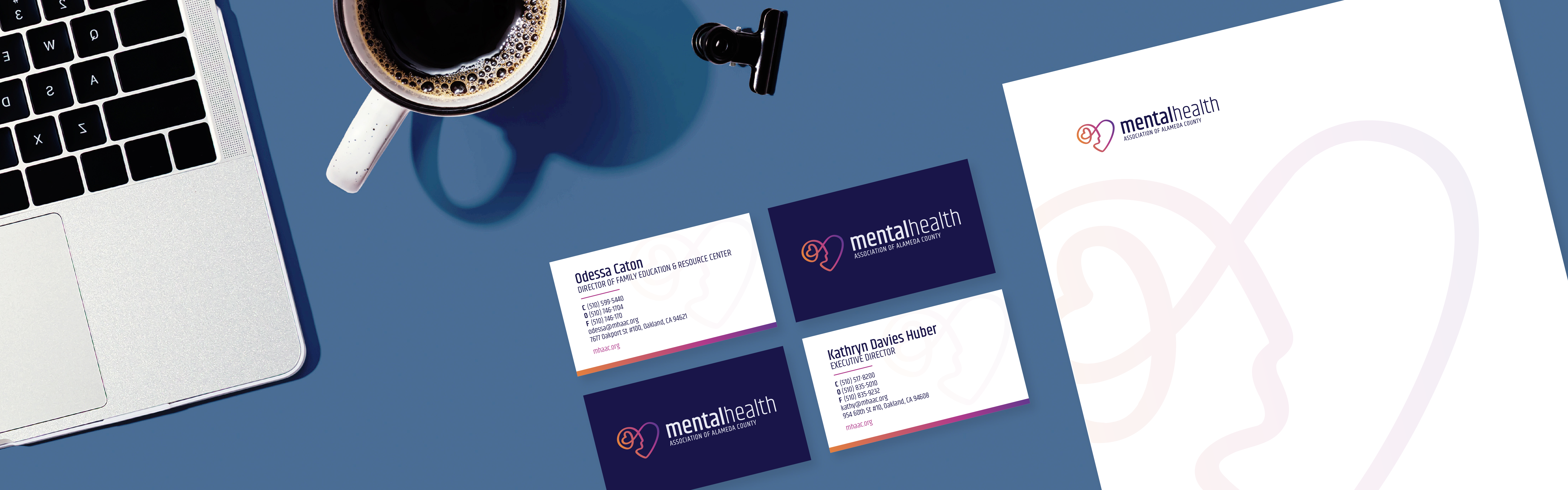 A neatly arranged workspace featuring a laptop, a cup of coffee, business cards, and stationery with Mental Health Association branding materials.
